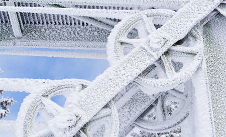 Frozen metal wheel or pulley covered in ice and snow on an exterior structure in harsh winter climatic conditionsの写真素材