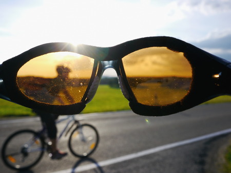 Sunnglasses in front of a cyclist driving down a streetの写真素材