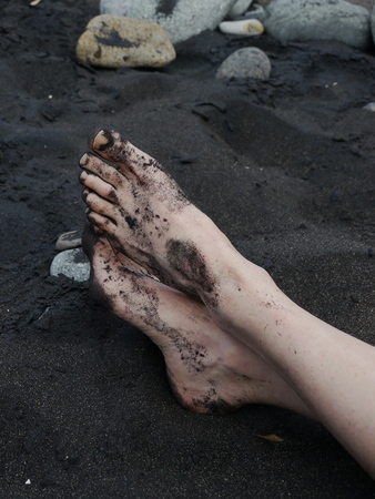 Man's barefeet in black sand in Maui, Hawaii.の写真素材