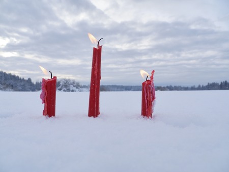 red candles on white snow background outside in winterの写真素材