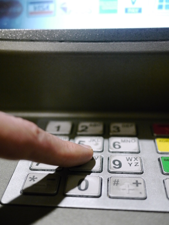 Finger using automatic teller keypad to enter pin numberの写真素材