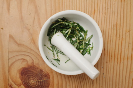 A bouquet of rosemary herbs on a weathered old chopping board.