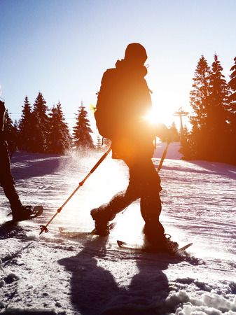 Cross country skier at sunrise or sunset moving through the snow with a sunburst over his shoulderの写真素材