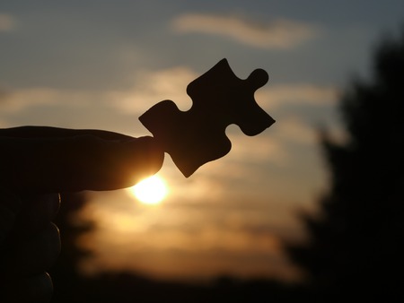 Pinch a piece of the jigsaw puzzleの写真素材