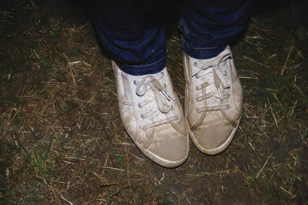 Person wearing jeans and sneakers or tackies, high angle close up view of the feet on grassの写真素材