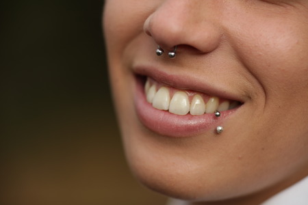 Toothy smile. Woman with piercing in nose and lip. Unrecognizableの写真素材
