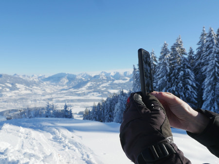woman photographing a winter landscape with her smartphoneの写真素材