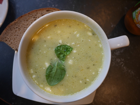 Broccoli soup in the white bowl decorated with basil leafの写真素材