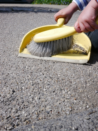 a little girl sweeps the dirt of a street in a paddleの写真素材