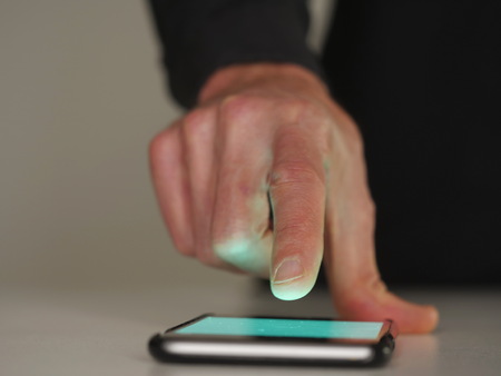 Close-up of man's finger touching screen of smartphone. Unrecognizable.の写真素材