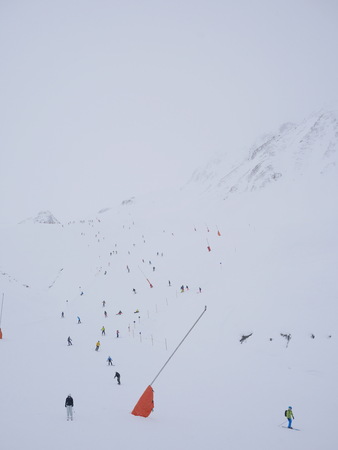 People skirunnign down a ski slope in mountains
