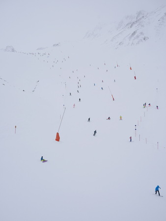 People skirunnign down a ski slope in mountains