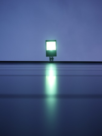 View from below on floodlight with green light against cloudy skyの写真素材