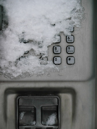 Payphone in winter, partially snow-covered.の写真素材