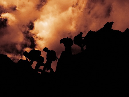 Climbers walking on rocks against of cloudy skyの写真素材