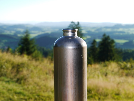 Metal water bottle in a green summer forestの写真素材