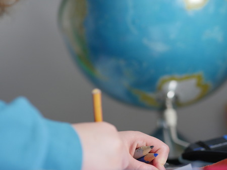 child hands writing in front of globe