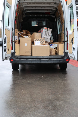 A white van is filled with boxes and is parked on a wet streetの写真素材