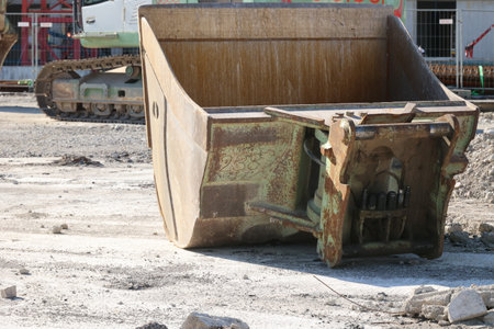 A large, rusty bucket sits on a dirt field