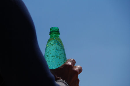 Person is holding a green bottle of waterの写真素材