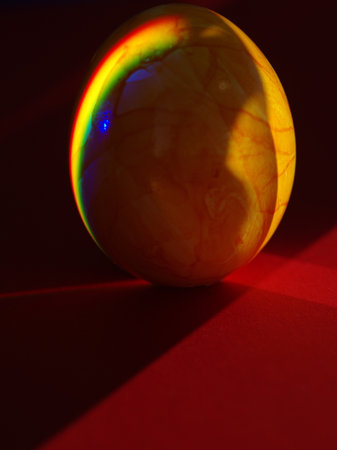 A yellow egg with a rainbow reflection on itの写真素材