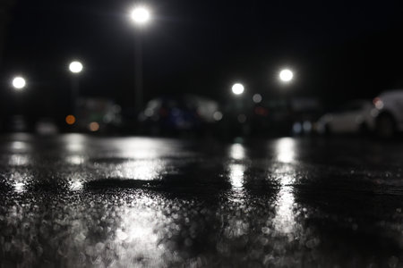 A blurry image of a parking lot at night with cars and a street lightの写真素材