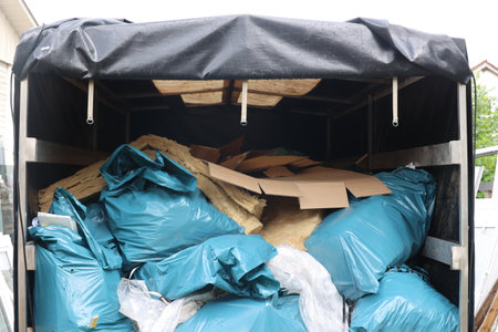 Dumpster is full of trash and has a blue tarp on top