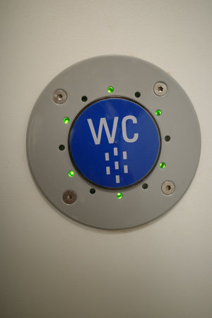 Round button with a blue and white sign that says WC