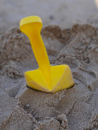 Yellow plastic shovel is sitting in the sand