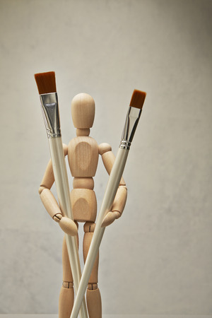 Wooden mannequin with paintbrushの写真素材