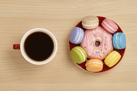 Coffee, colorful macaron and doughnut on wooden tableの写真素材