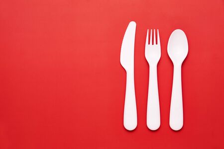 Plasic white cutlery set with red background. Top viewの写真素材