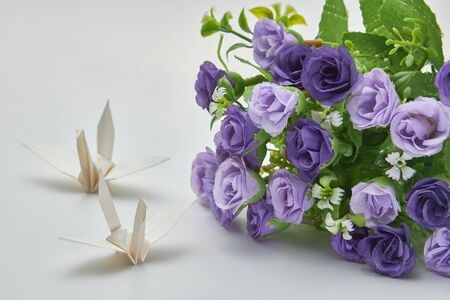 White origami crane and purple flowers, shallow depth of fieldの写真素材