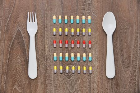 Spoon Fork colorful tablets and capsules on wooden background. Health care conceptの写真素材