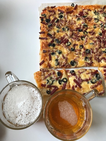 Ready pizza, cut into slices and beer. Nearby there are scissors.の素材