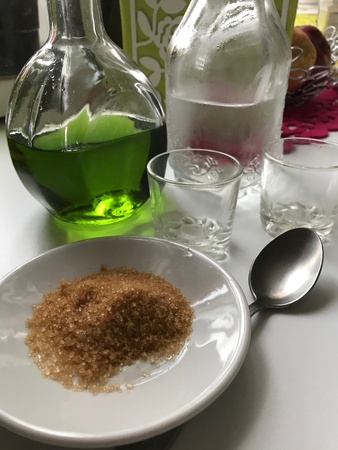 A bottle of absinthe, cold water and sugar are on the table before preparing a cocktail. Nearby are glasses for consumptionの素材