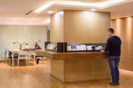 Man Reading In A Study Room with People Passing Byのeditorial素材