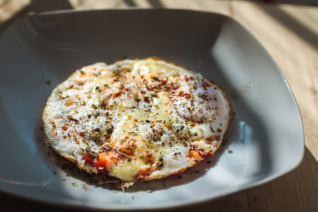 Fried eggs with cheese and spices for breakfast in the morning lightの写真素材