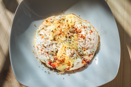 Fried eggs with cheese and spices for breakfast in the morning lightの写真素材