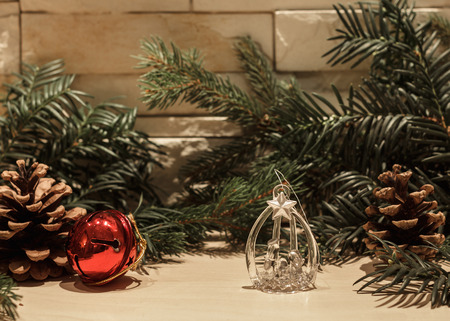 Glass Christmas decoration, one red bell, two pine cones and some green pine branchesの写真素材