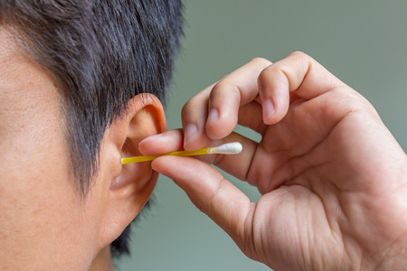 male cleaning ear with cotton bud