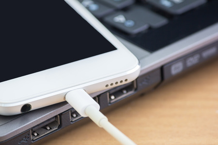 smartphone and usb cable on laptop computerの写真素材