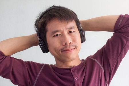 Happy asian man is listening to the musicの写真素材