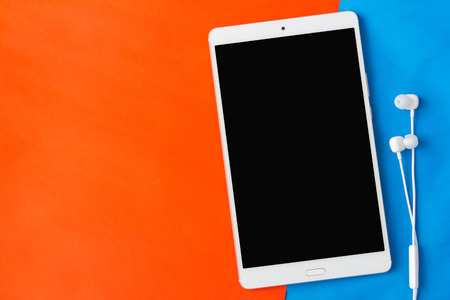 tablet with earphone in top view on orange and blue backgroundの写真素材