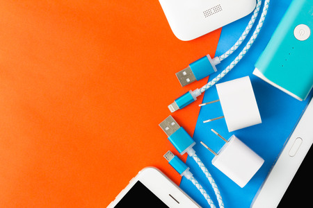 USB charging cables for smartphone and tablet in top view on blue and orange background