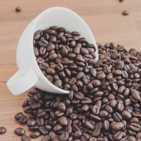 roasted coffee beans in white cup on table