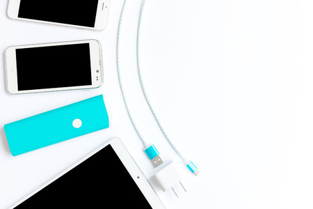 white smartphone with battery bank and usb charging cables in top view