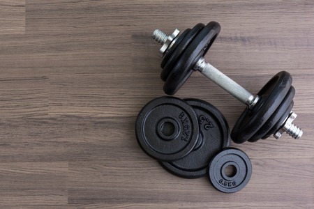 black dumbbell on wooden floor in top viewの写真素材