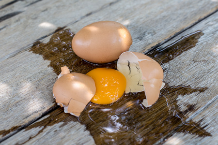 Broken egg on a wooden cutting board on wooden background.の写真素材