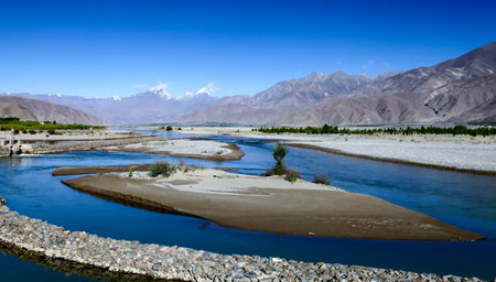 The Lhasa River in Tibet, China, and the snow-capped mountains in the distanceの写真素材